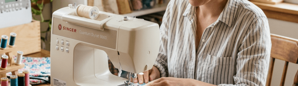 Woman sewing floral fabric with Singer sewing machine at wooden table